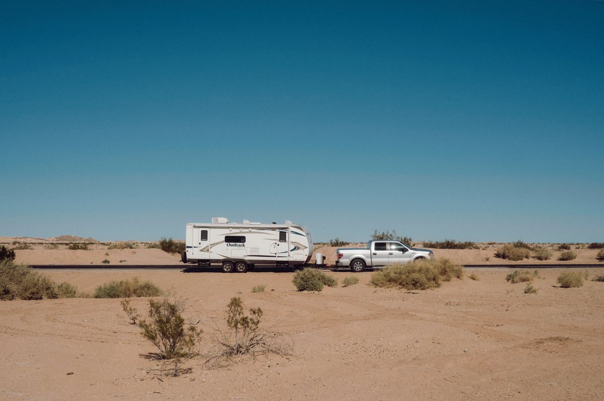 Truck and travel trailer stopped on open desert with scrubland stretching to the hills